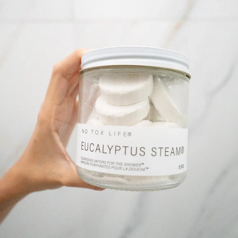 Jar of Eucalyptus Steam product held by a hand against a neutral background